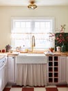 Kitchen with farm sink and curtain underneath